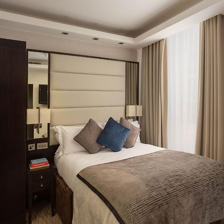 Hotel Montcalm Brewery Townhouse London Exterior foto The image shows a cozy bedroom. It features a comfortable double bed with a light-colored duvet and decorative pillows in shades of blue and gray. The headboard is upholstered in a soft material, and there are bedside lamps on either side of the bed.