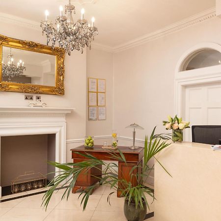 Hotel Montcalm Brewery Townhouse London Exterior foto The photo shows a stylish reception area. There is a decorative chandelier hanging from the ceiling, providing elegant lighting. A large, ornate mirror is mounted on the wall beside the fireplace, which features a simple, classic design. In front of 