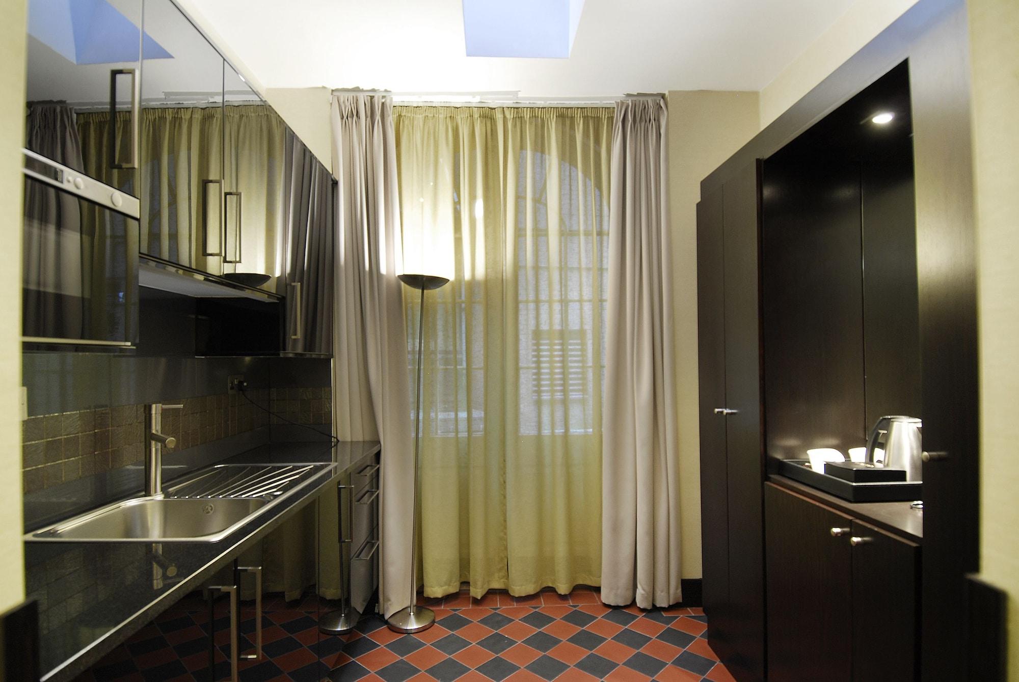 Hotel Montcalm Brewery Townhouse London Exterior foto The photo shows a modern kitchen space. On the left side, there is a sleek countertop and kitchen cabinets in a dark finish. The backsplash appears shiny, reflecting the surroundings. To the right, there is a tall black cabinet. A window is covered w