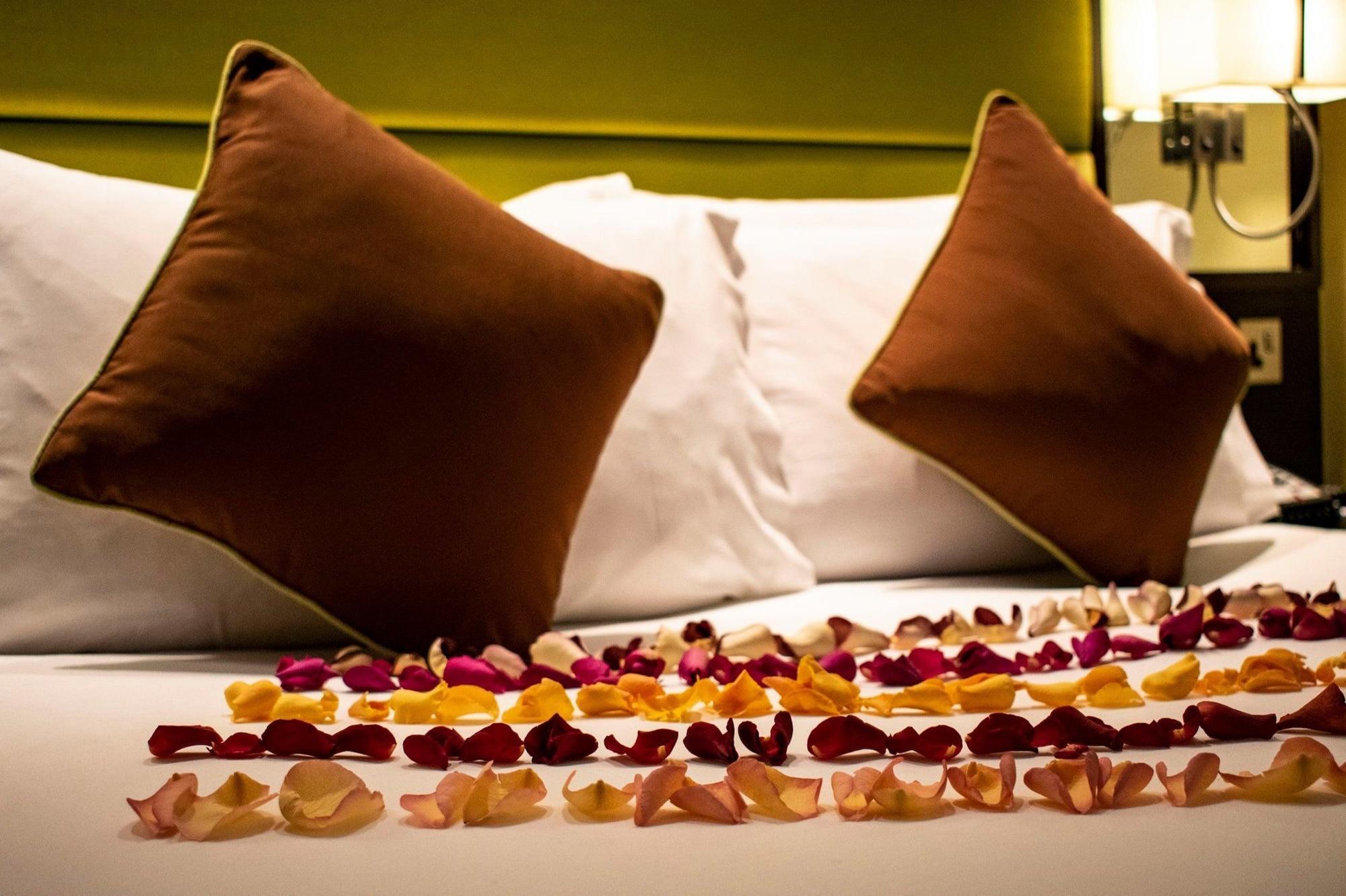 Hotel Montcalm Brewery Townhouse London Exterior foto The photo shows a neatly arranged bed with two white pillows and brown decorative cushions. Scattered across the bed is a decorative display of flower petals in various colors, including pink, yellow, and orange, creating a romantic or tranquil ambia