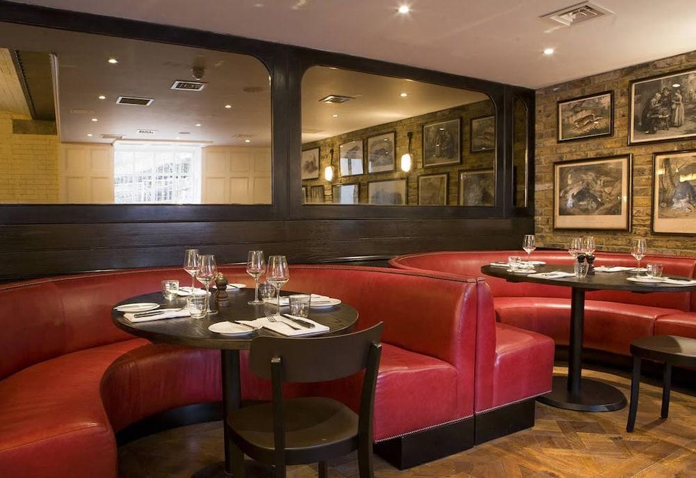 Hotel Montcalm Brewery Townhouse London Exterior foto The image shows the interior of a restaurant featuring a warm and inviting atmosphere. There are several round tables surrounded by black chairs, with red, upholstered booths lining the walls. The decor includes framed artwork hanging on the walls, a