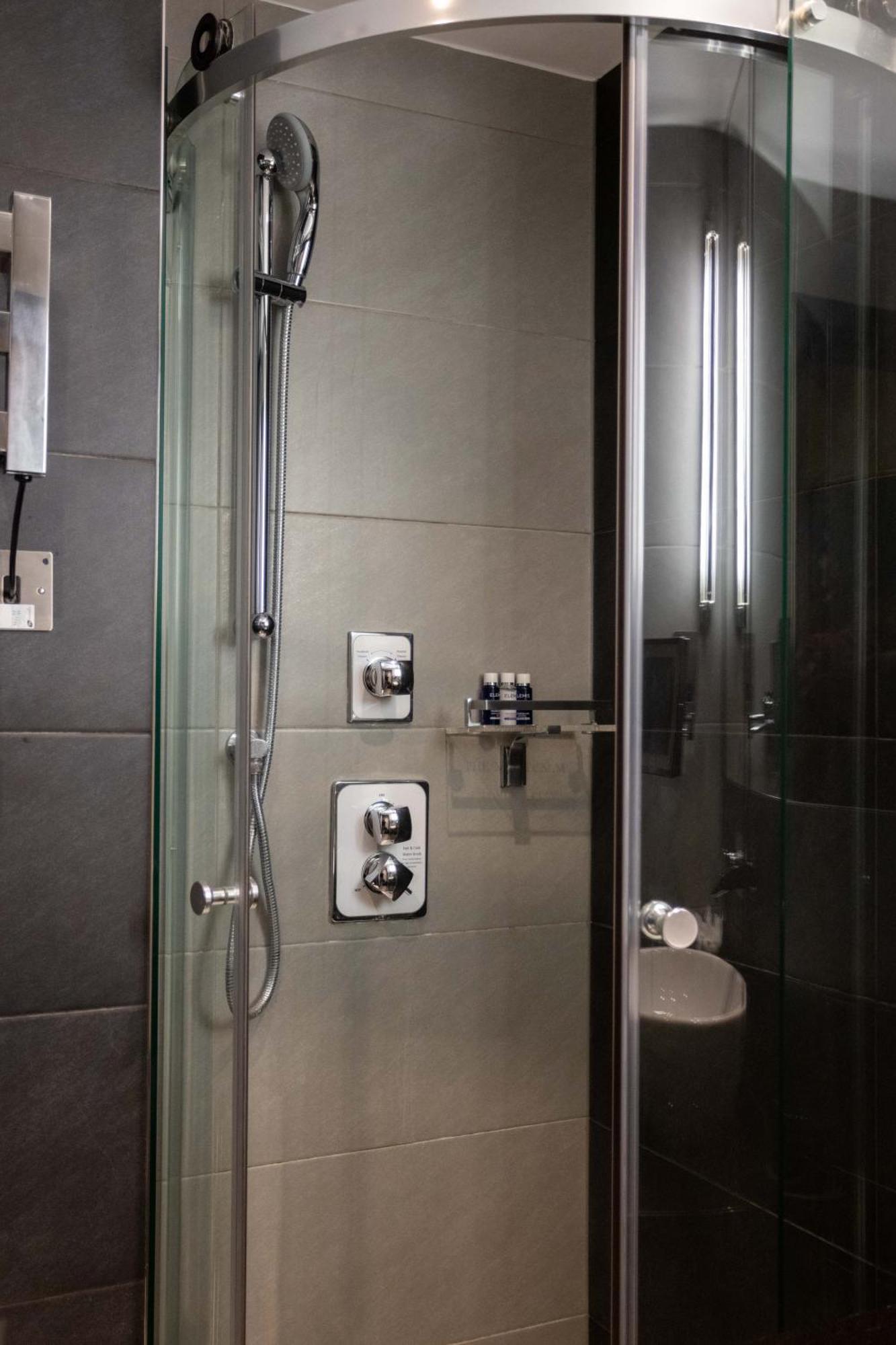 Hotel Montcalm Brewery Townhouse London Exterior foto The photo shows a modern shower area. It features glass panels and tiled walls in a neutral color palette, creating a sleek and contemporary look. There are two main control panels for adjusting the water temperature and pressure, with various knobs 