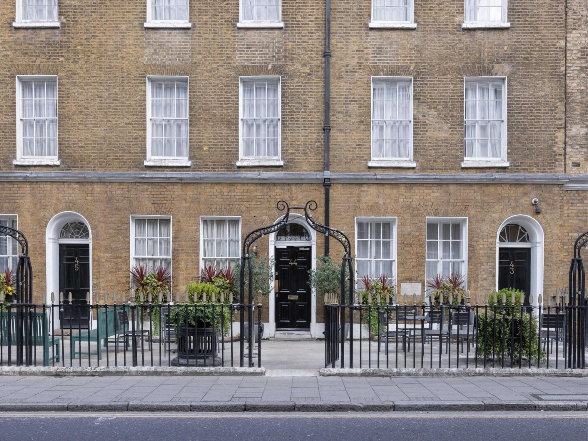 Hotel Montcalm Brewery Townhouse London Exterior foto The photo shows a row of three-story brick buildings, featuring a classic design with large windows and decorative ironwork. The buildings are painted in a muted yellow-brown color, typical of older urban architecture. In front of the buildings, ther