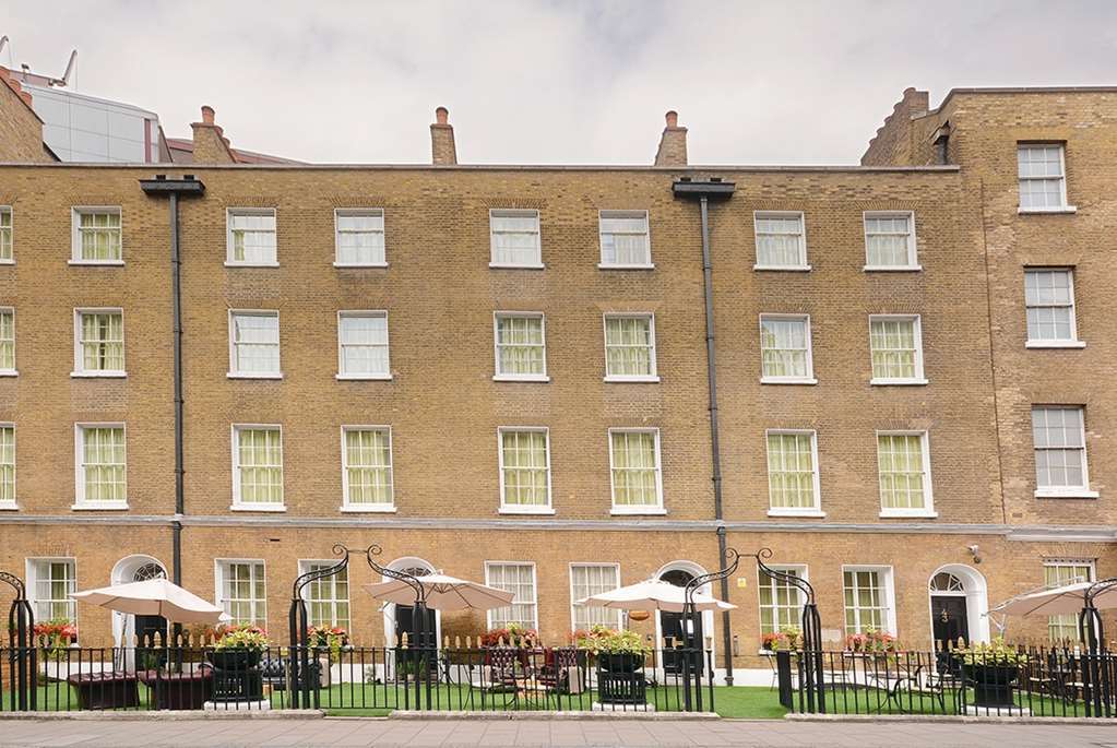 Hotel Montcalm Brewery Townhouse London Exterior foto The photo shows a brick building with several windows on its facade. The structure appears to be three stories tall, featuring a symmetrical design with multiple windows that have white frames. In front of the building, there is a landscaped area wit