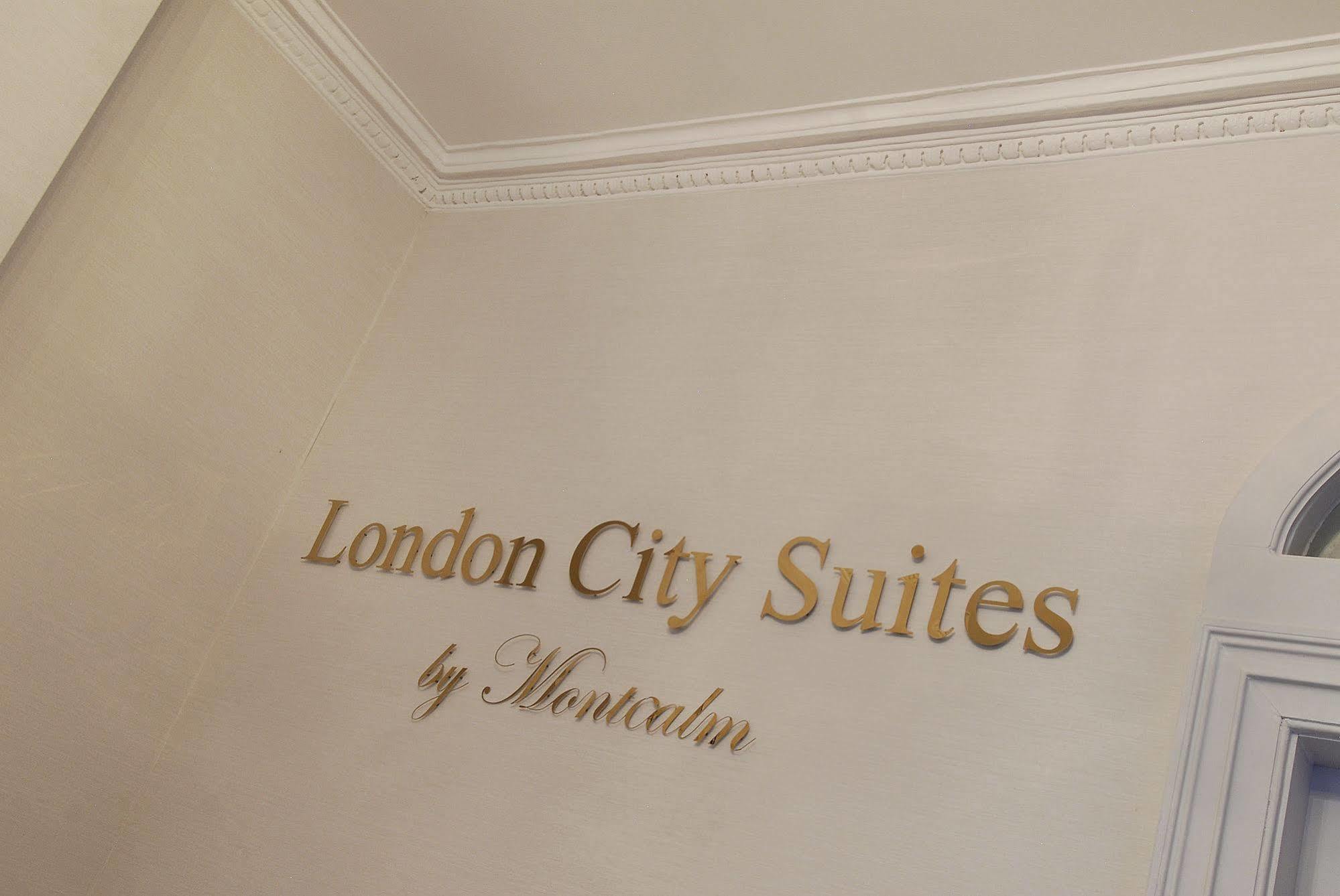 Hotel Montcalm Brewery Townhouse London Exterior foto The photo shows a wall display featuring the text "London City Suites" in a bold, gold-colored font. Below that, the words "by Montcalm" are written in a smaller, elegant style. The background appears to be a neutral-colored wall, possibly in a hotel