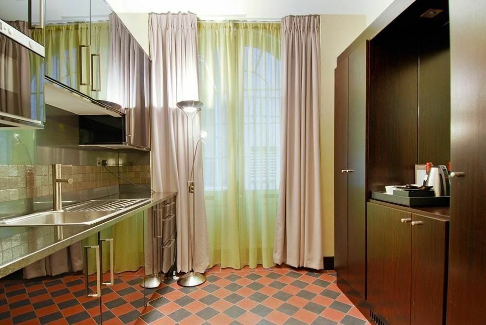 Hotel Montcalm Brewery Townhouse London Exterior foto The photo shows a modern kitchen area. There is metallic cabinetry and a stainless steel countertop with a sink. The walls are adorned with light-colored curtains that allow natural light to filter in, with one set in a soft purple hue and another in