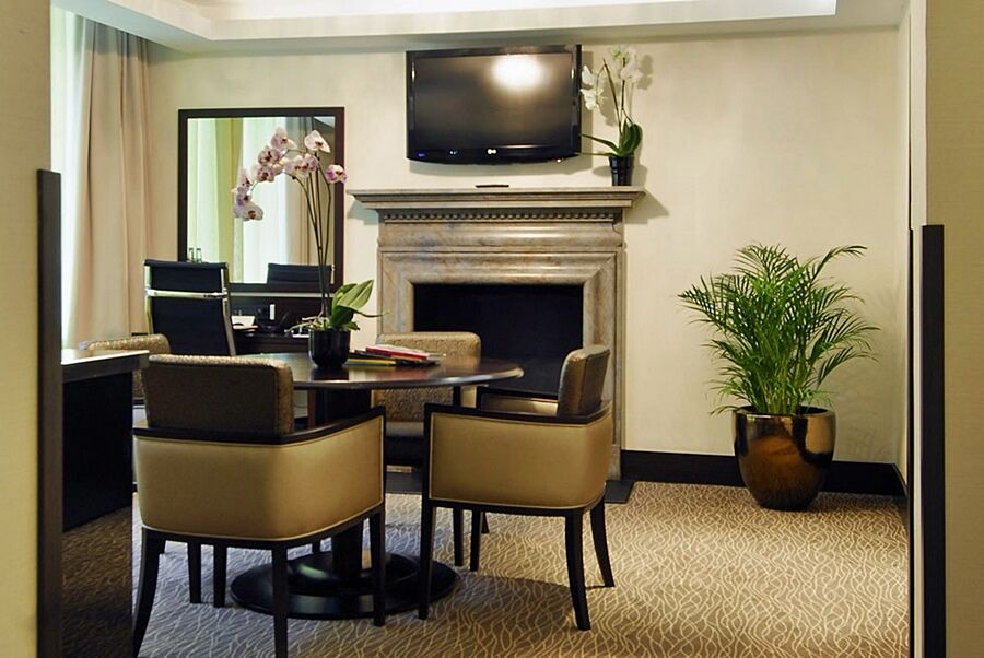 Hotel Montcalm Brewery Townhouse London Exterior foto The photo shows a modern and stylish room with a dining or meeting area. There is a round table surrounded by four upholstered chairs. A flat-screen television is mounted on the wall above a decorative fireplace. To the side, there is a mirror reflec