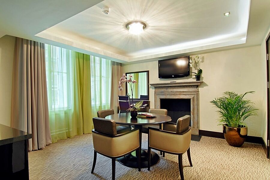 Hotel Montcalm Brewery Townhouse London Exterior foto The photo shows a well-furnished room, likely a hotel suite or a modern living space. It features a round dining table with four comfortable chairs. The walls are adorned with light-colored decor, and there are large windows with sheer and solid curt